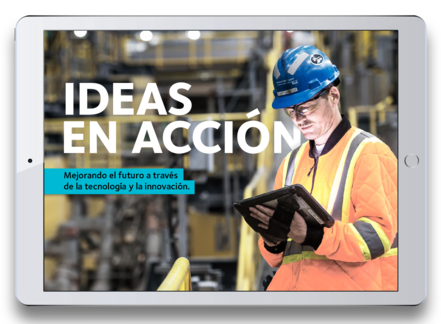 Worker in safety gear using a tablet in an industrial setting. Text: Ideas en Acción.